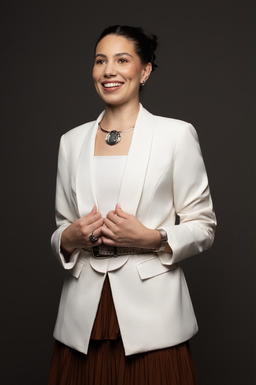 Dra. Nathália Cardoso de blazer branco, sorrindo, em fundo escuro